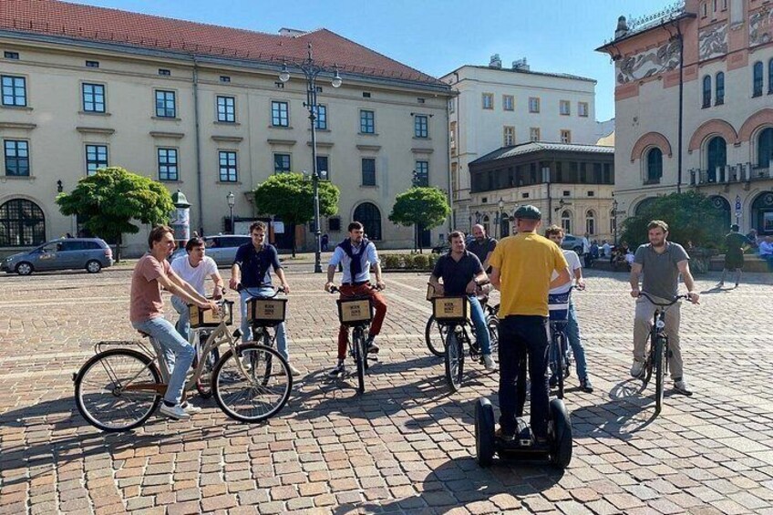 Een groep mensen fietst over een geplaveid straatje met historische gebouwen op de achtergrond. 5