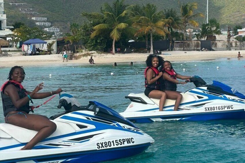 Dos motos acuáticas sobre aguas tranquilas con una playa y palmeras al fondo. 3