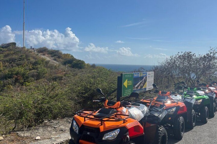 Unos cuatrimotos alineadas en un camino de tierra, con un cartel al fondo. 4