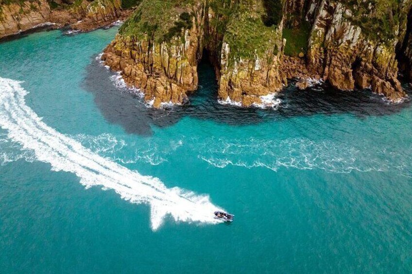 Un bateau navigue sur une mer turquoise, le long d’une côte rocheuse bordée de falaises. 5