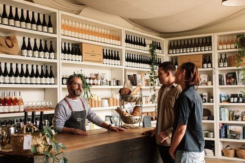 Une cave à vin avec des étagères remplies de bouteilles et un comptoir derrière lequel se tient une personne. 4