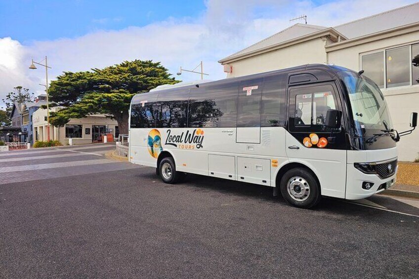 Un autobus blanc, arborant le logo de la compagnie « Local Way Tours », est garé dans une rue. 1