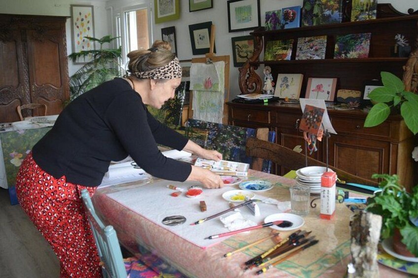 Une personne est assise à une table et peint, entourée de matériel de dessin. 3