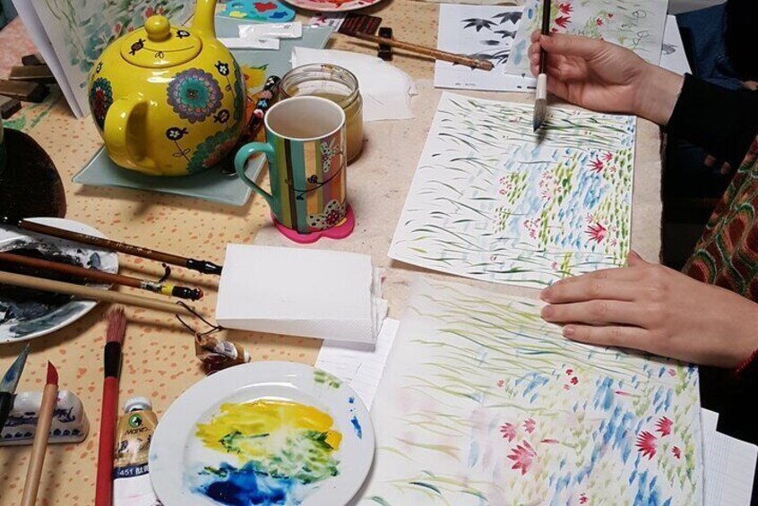 Una persona pintando sobre un lienzo con pinceles y una paleta de colores. 1