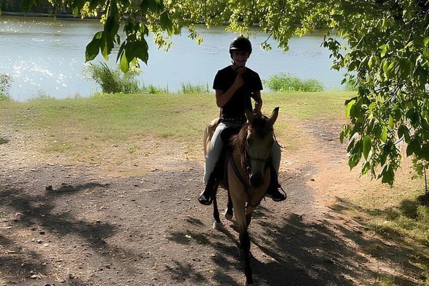A person riding a horse along a dirt path near a body of water. 2