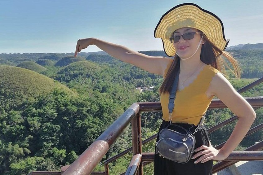 A person standing on a railing overlooking a forested landscape. 2