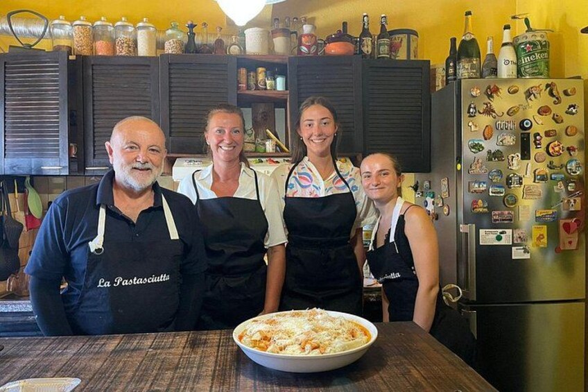 Four people standing in a kitchen with a large bowl of food on the counter. 3