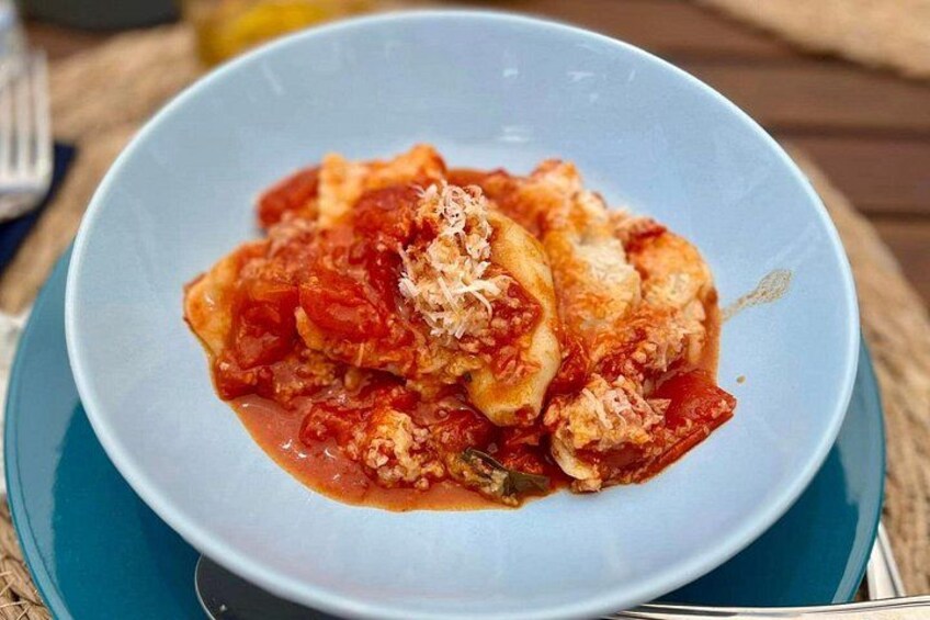 A plate of ravioli with tomato sauce and grated cheese. 1