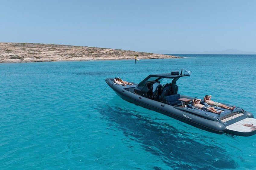 Ein Motorboot auf türkisfarbenem Wasser mit einer felsigen Küste im Hintergrund. 1