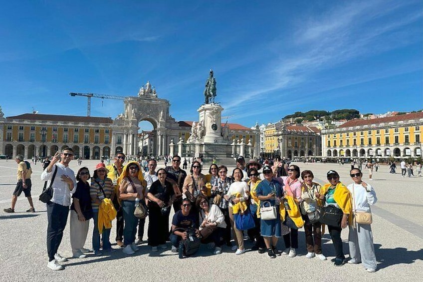 A group of people posing in a public square with a historical monument in the background. 5