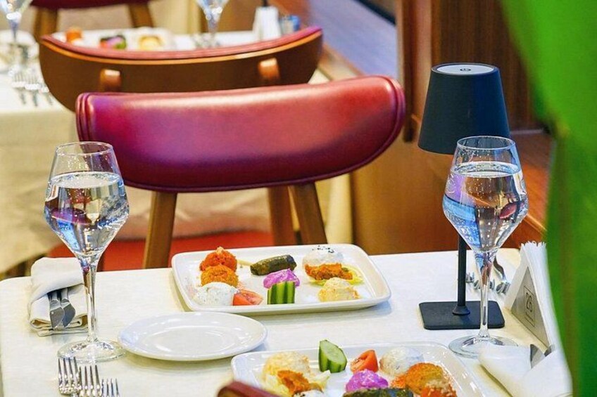 A dining table with plates of food, wine glasses, and a menu. 3