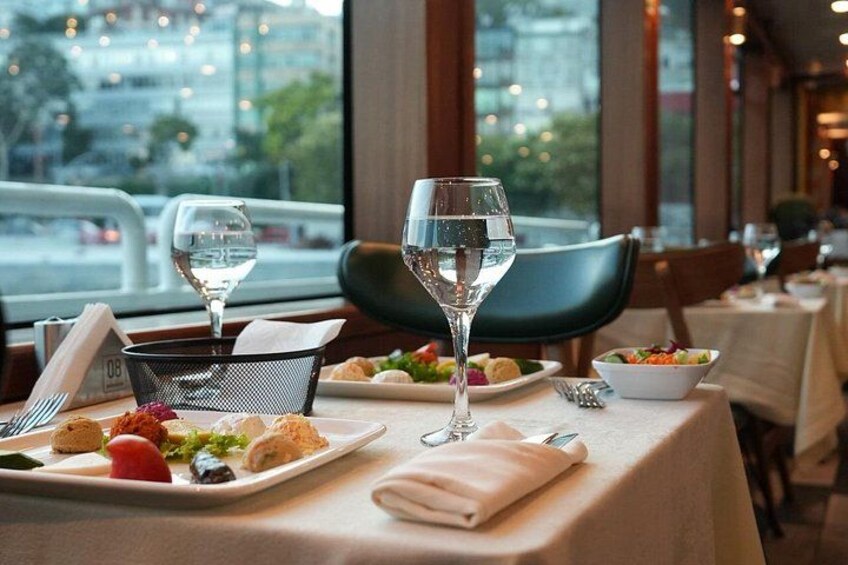 A restaurant table with plates of food, glasses of water, and a window view. 2
