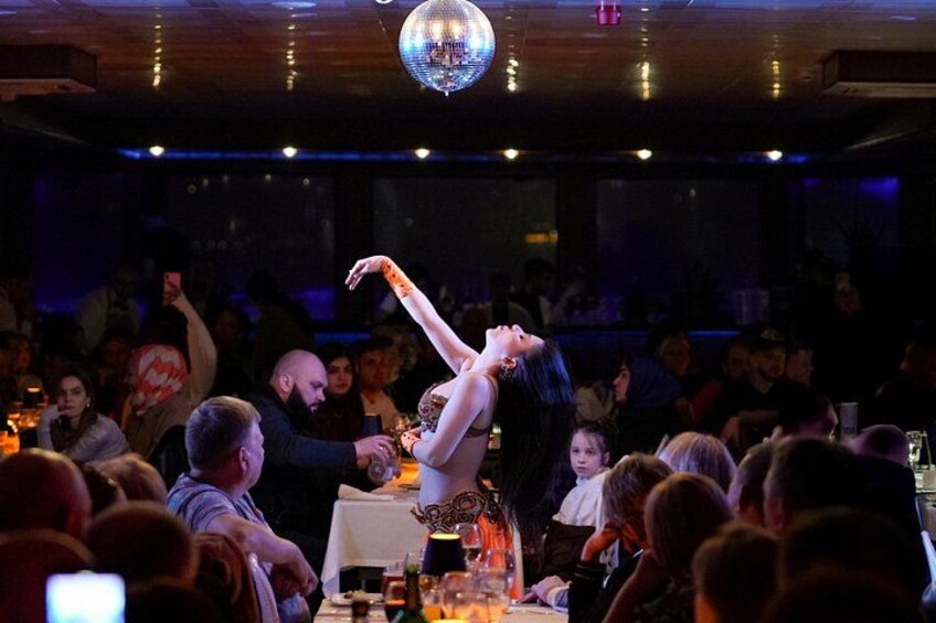 A person performing a balancing act on a table in a dimly lit room with an audience watching. 4