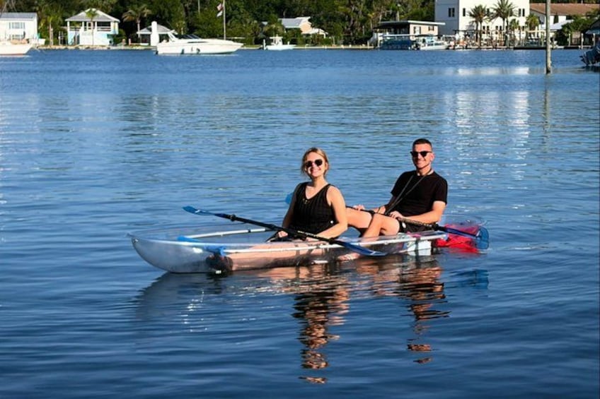 Two people in a kayak on calm water with houses in the background. 1