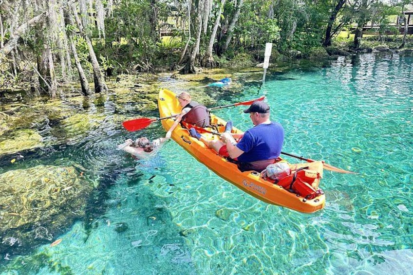 A man kayaking on a clear river surrounded by trees. 4