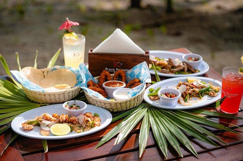 A picnic setup with plates of food, baskets, and a drink on a wooden table. 2