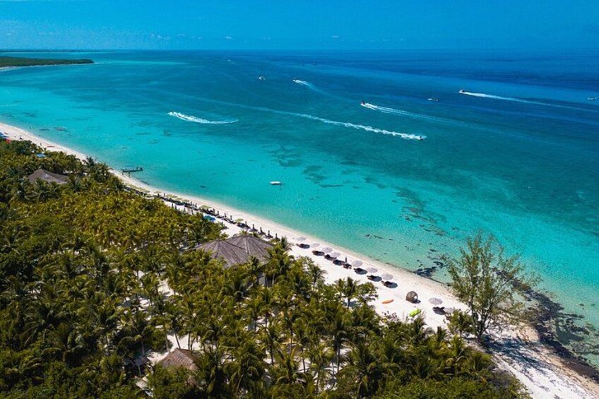A tropical beach with clear turquoise waters, white sand, and lush greenery. 3