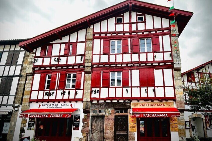 Ein traditionelles Gebäude mit roter und weißer Fassade, mit zwei Schaufenstern, auf denen 2