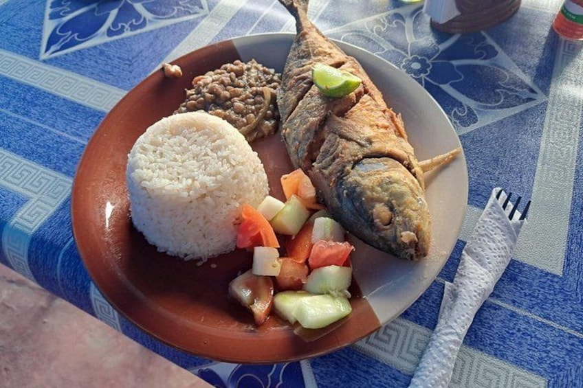 Un plato con un pescado entero, arroz blanco y una guarnición de verduras picadas. 5
