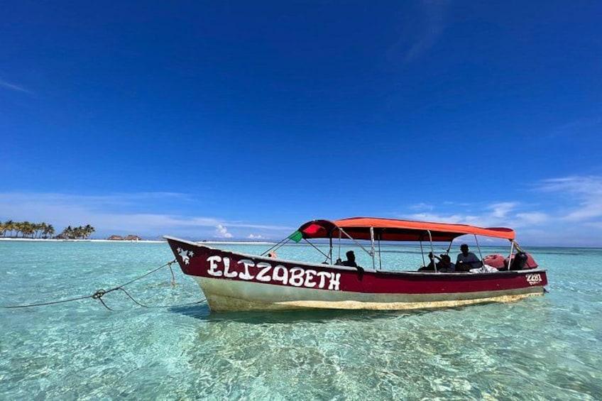Un bote llamado 'ELIZOBETH' anclado en aguas turquesas cristalinas bajo un cielo azul despejado. 2