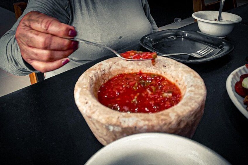 Una persona sirve comida de un cuenco de piedra con una cuchara. 4