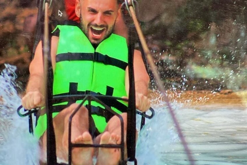 Une personne portant un gilet de sauvetage vert se trouve à bord d’un embarcation, et de l’eau éclabousse tout autour. 3