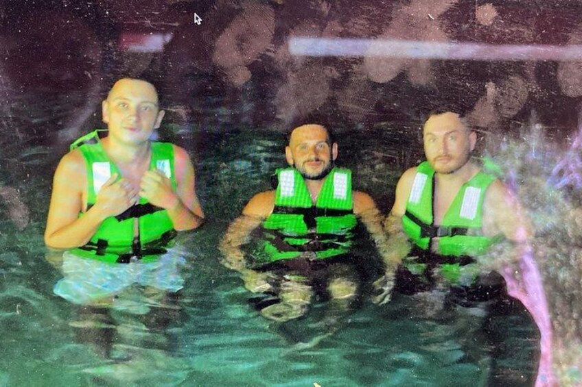 Trois personnes dans une piscine, portant des gilets de sauvetage verts. 2