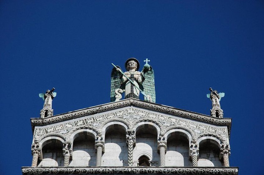 Un bâtiment doté d’éléments architecturaux décoratifs, notamment des statues et une croix au sommet. 3