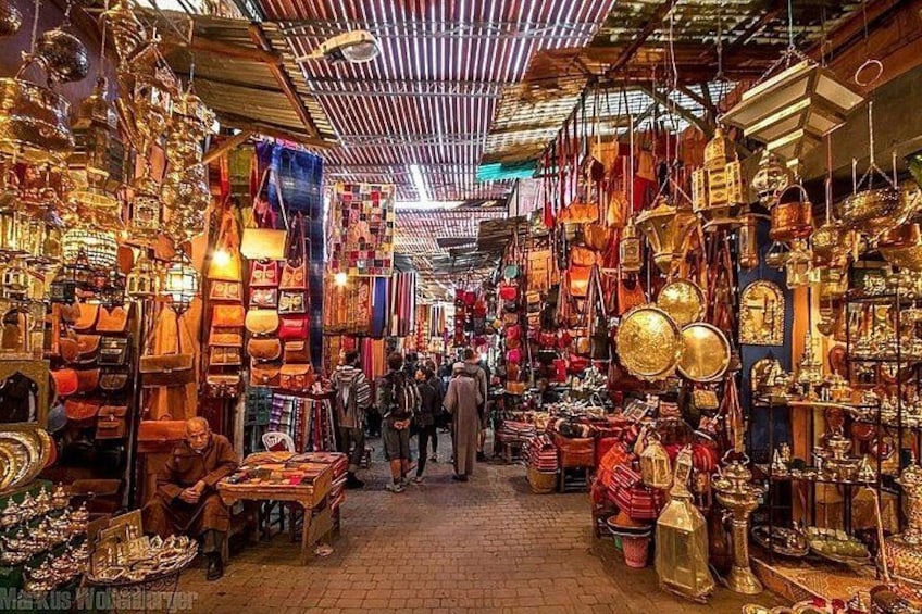 A bustling market with various stalls selling bags, jewelry, and other goods. 3