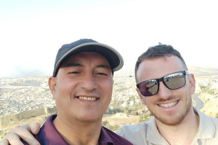 Two individuals standing with a cityscape in the background. 4