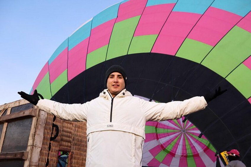 Een persoon staat voor een kleurrijke luchtballon. 3