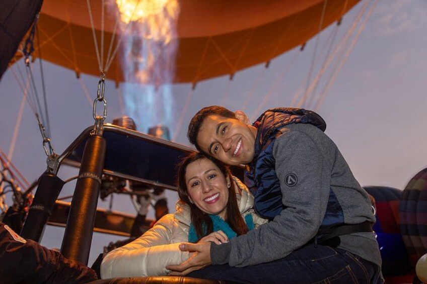 Een luchtballon met een mandje en een persoon die over de zijkant leunt. 5