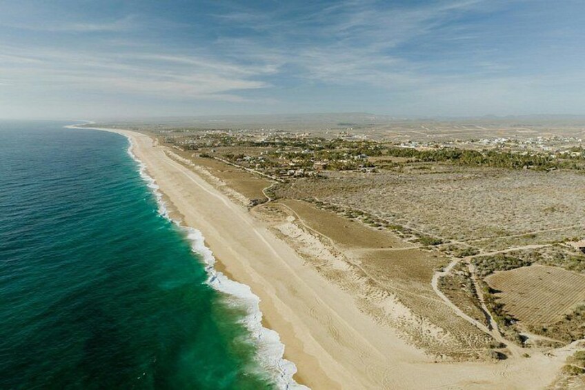 Un paysage côtier avec une plage de sable, des vagues de l’océan et une silhouette de ville qui se dessine à l’horizon. 2