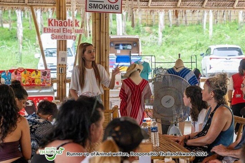 A group of people at an outdoor event with a sign indicating 'Khaolak Ethical Elephant Sanctuary'. 4