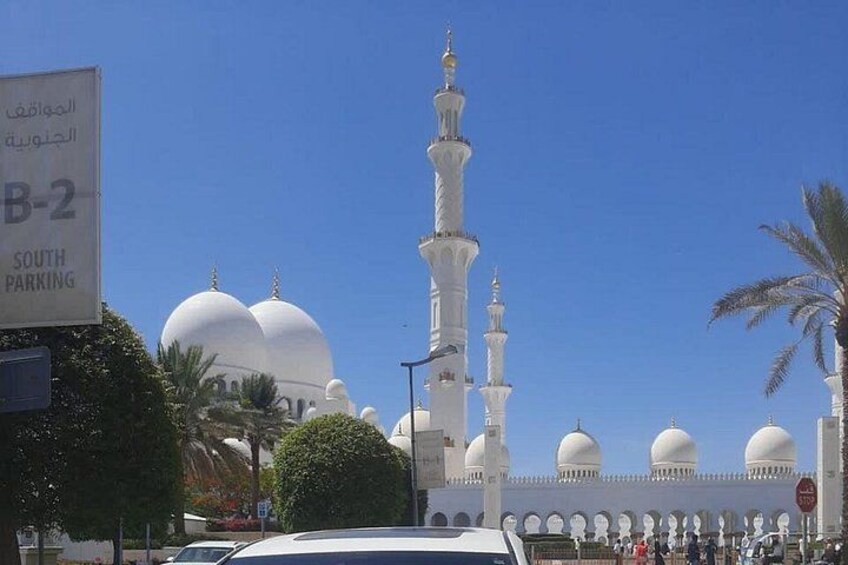 Een moskee met meerdere koepels en minaretten, een parkeersbord en palmbomen. 1