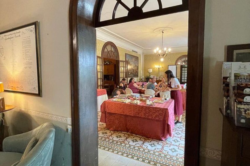 A dining area with a table set for a meal, a chandelier, and a framed menu on the wall. 2