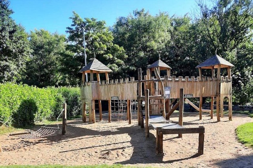 A wooden play structure with multiple levels and lookout towers. 5