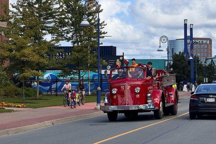 A vintage fire truck with people riding bicycles on the sidewalk. 2
