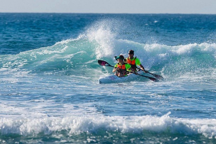 Dos personas haciendo kayak sobre una ola. 3