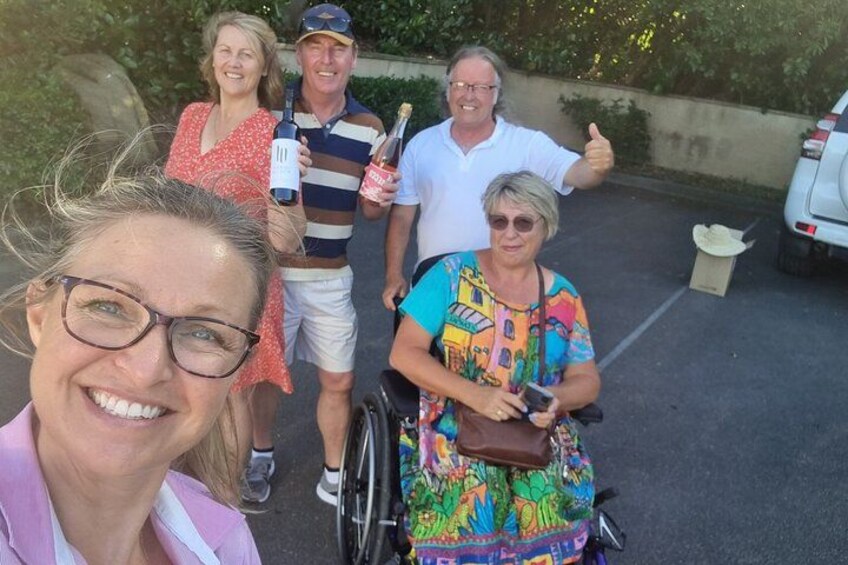 A group of people in a parking lot, some holding drinks and one in a wheelchair. 5