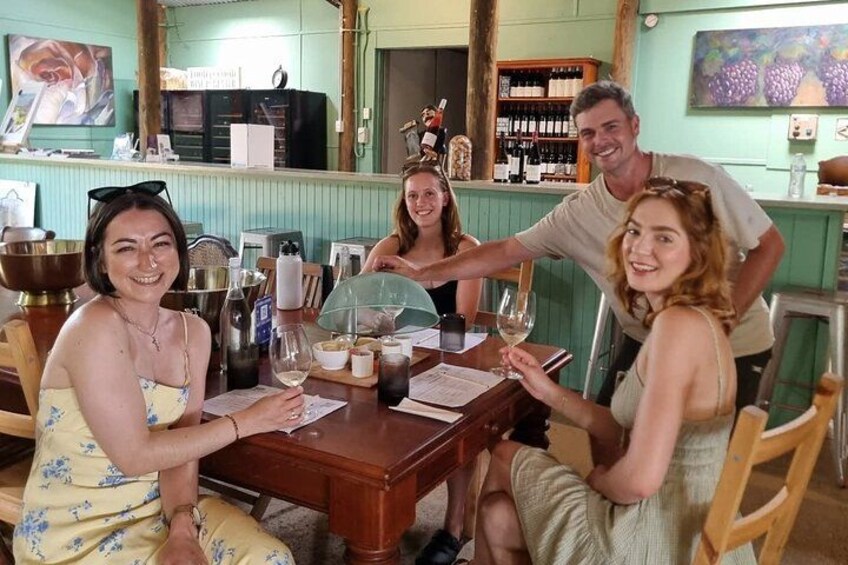A group of people sitting at a table in a restaurant with wine glasses and bottles. 3