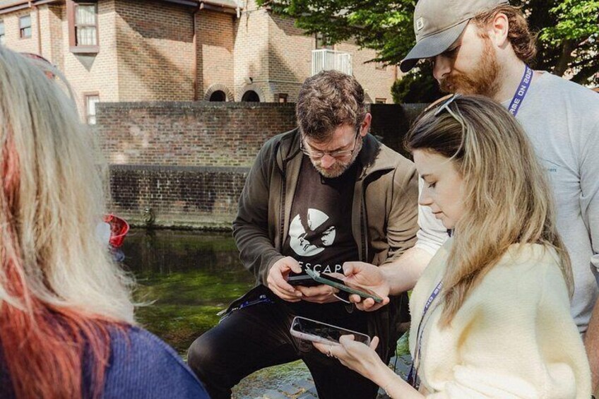 A group of people gathered around a person using a smartphone. 5