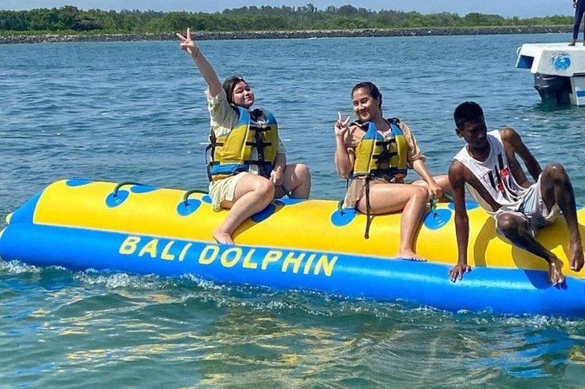 Drei Personen in einem blauen und gelben Schlauchboot mit der Aufschrift 'BALI DOLPHIN' auf dem Wasser. 2