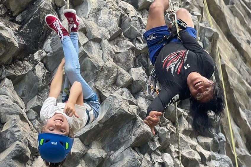 Two people rappelling down a rocky cliff. 4