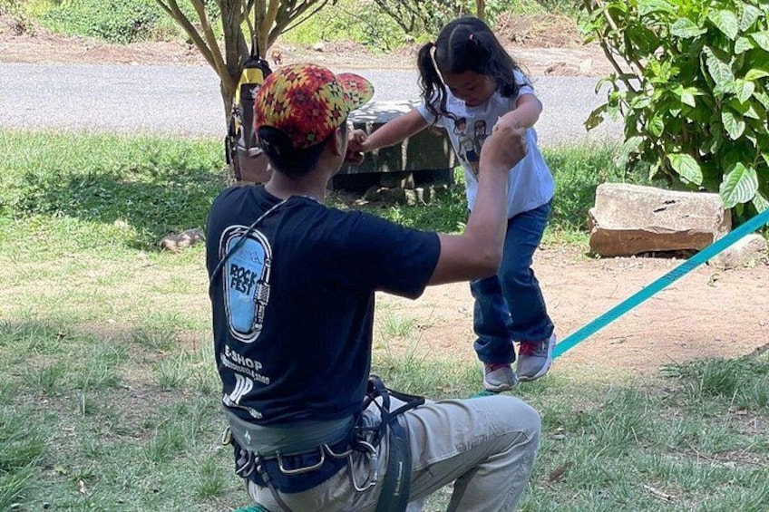A person in a blue shirt with a logo, kneeling and holding a child. 5