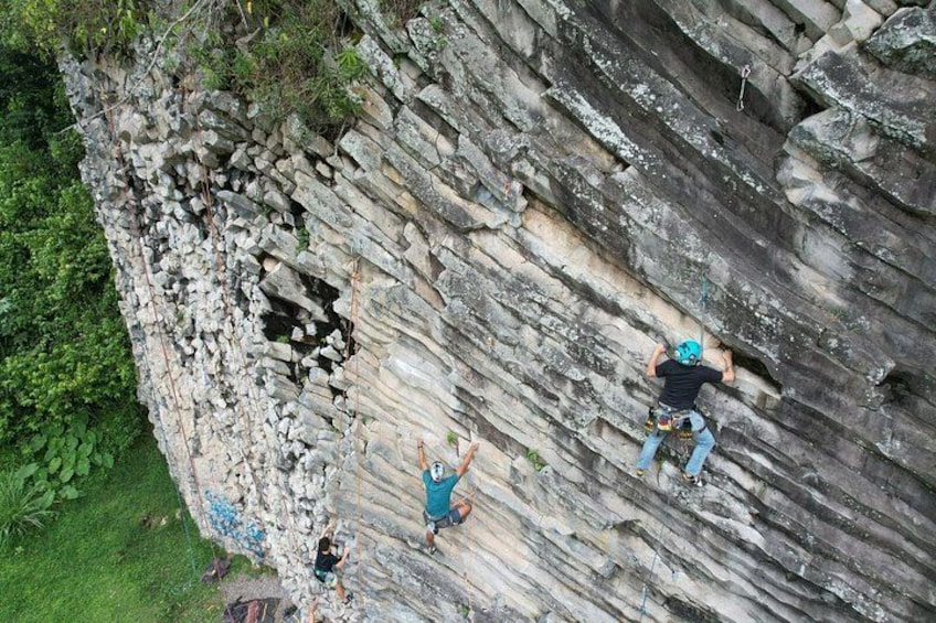 A person climbing a rocky cliff with a helmet and harness. 1