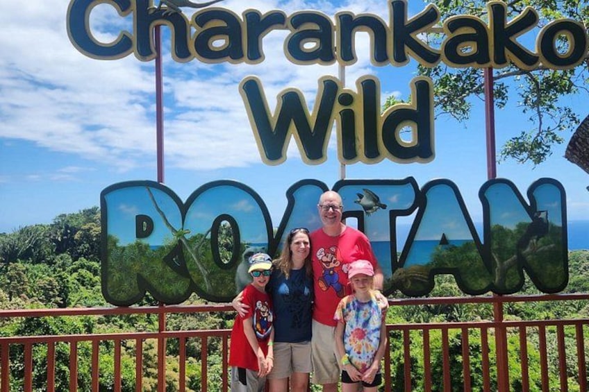 A family posing in front of a sign for Charankako Wild. 2