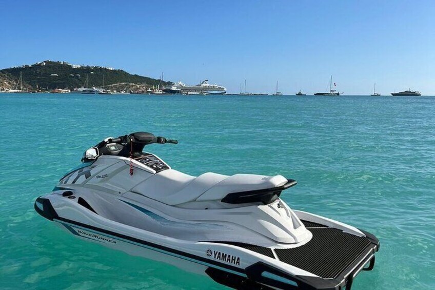 A Yamaha jet ski on clear turquoise water with a coastal landscape in the background. 1