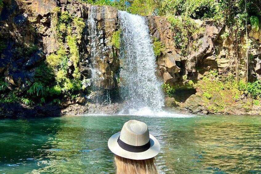 A waterfall cascading into a clear pool surrounded by rocky cliffs and greenery. 4