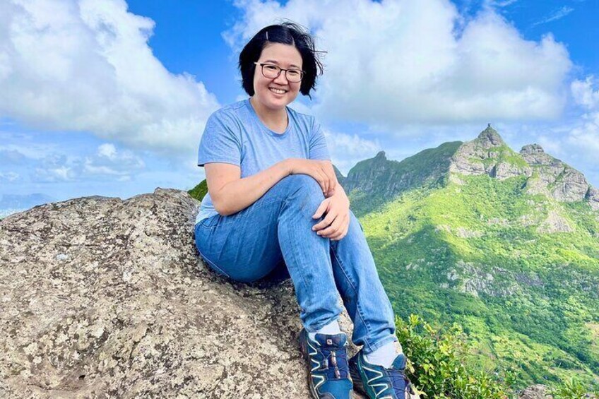 A person sitting on a rock with a mountainous landscape in the background. 5